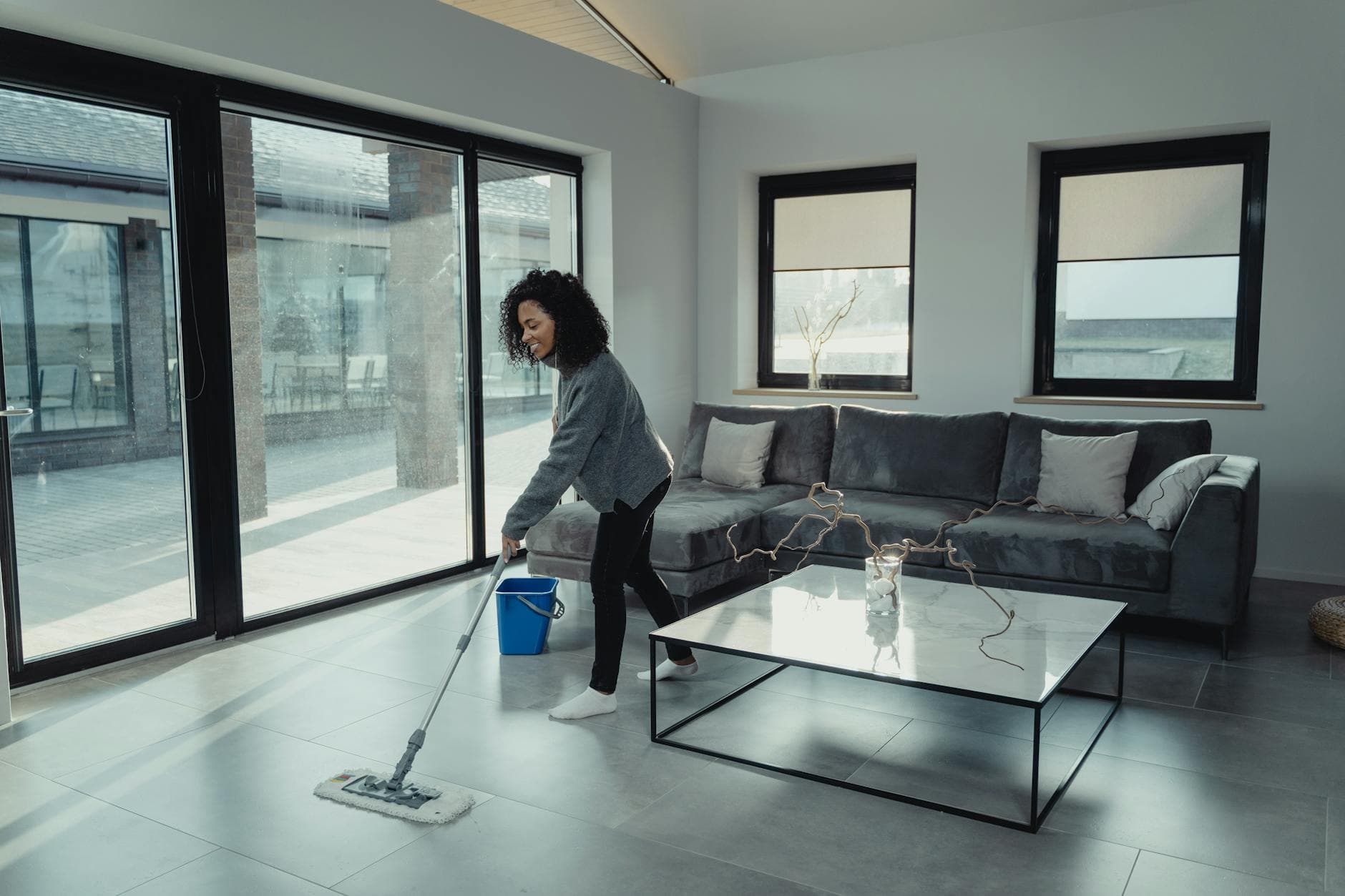 House cleaner mopping a bright, modern Pennsylvania apartment with large windows — cleaning services in Chestnut Hill, Philadelphia