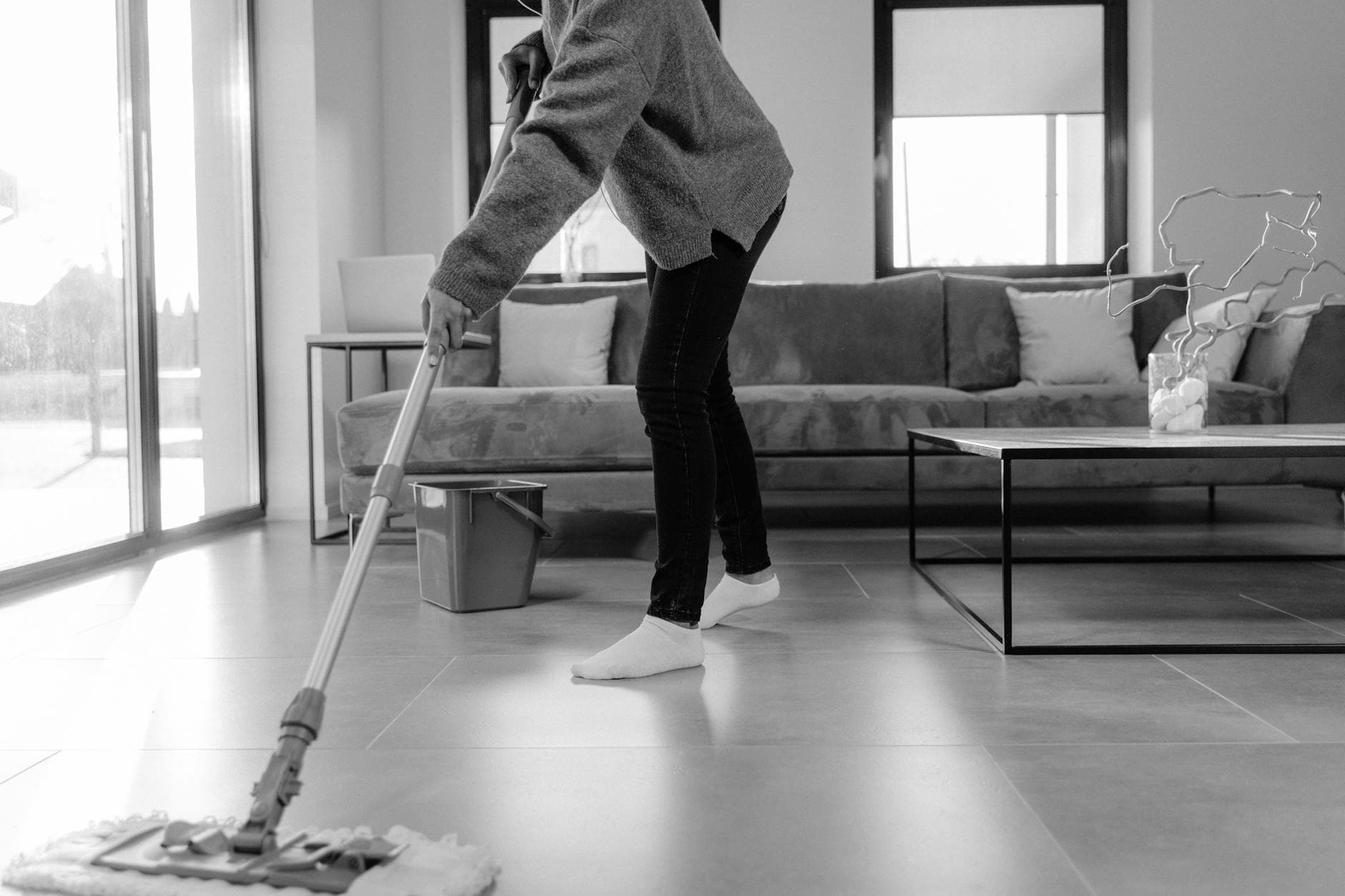 Professional Pennsylvania cleaner mopping the floor in a modern apartment living room — Weekly Maid Service in Chestnut Hill, Philadelphia